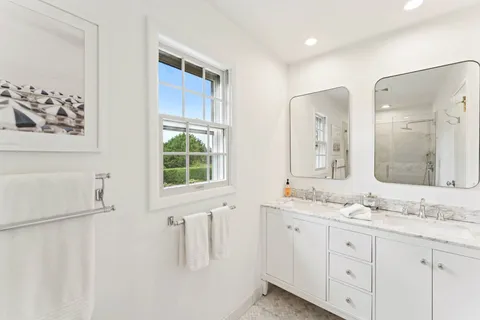 a bathroom with a double vanity sink window and a mirror
