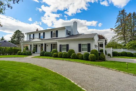 a front view of a house with a yard and potted plants