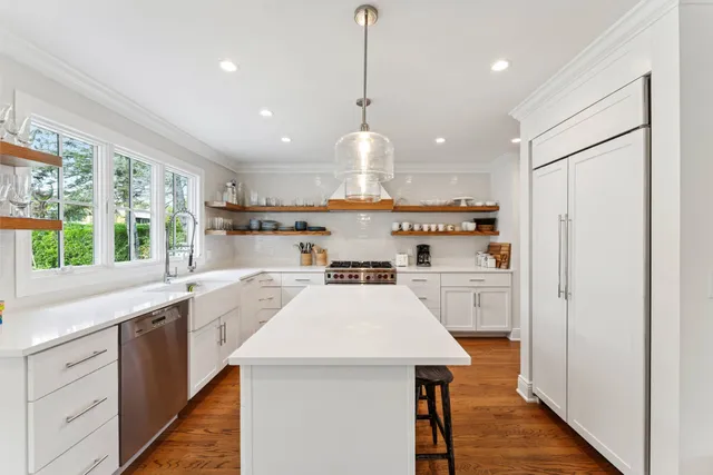 a kitchen with kitchen island a sink appliances and a large window