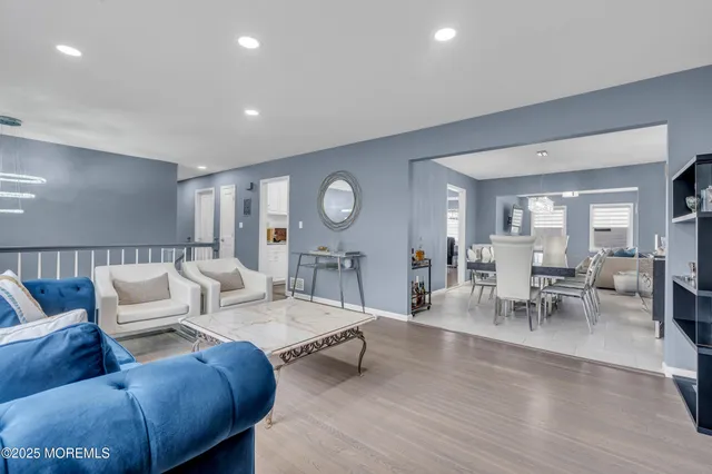 a living room with furniture kitchen view and a wooden floor