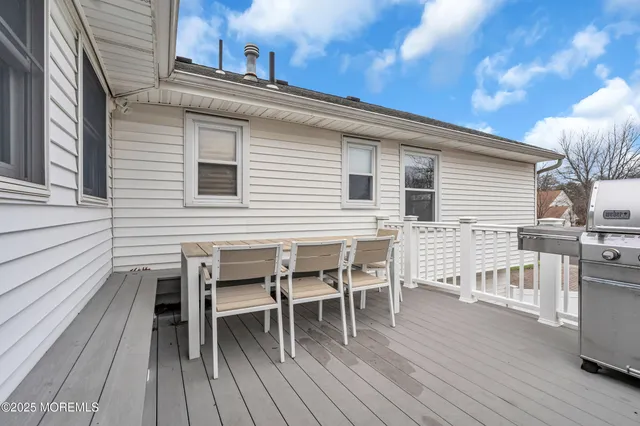 a view of a roof deck with table and chairs a barbeque with wooden floor and fence