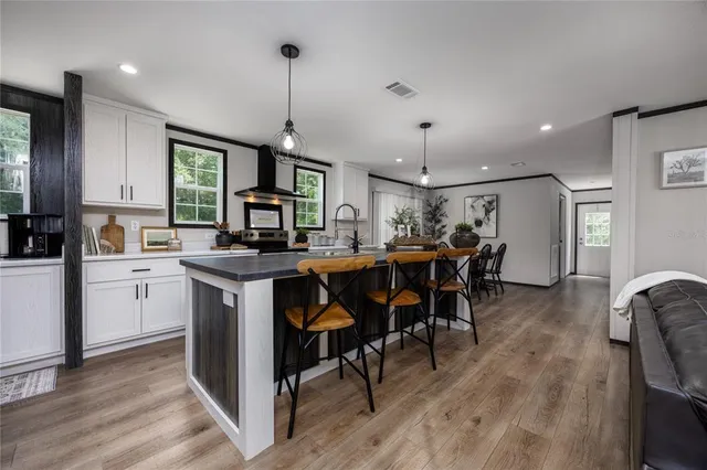 a open kitchen with stainless steel appliances granite countertop a stove refrigerator and a dining table with wooden floor