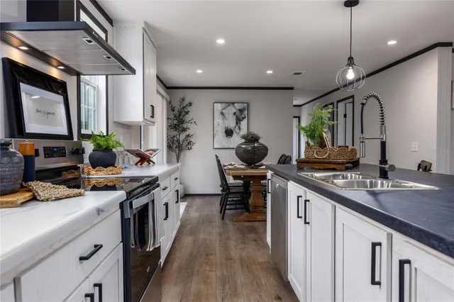 a kitchen with stainless steel appliances granite countertop sink stove and wooden floor