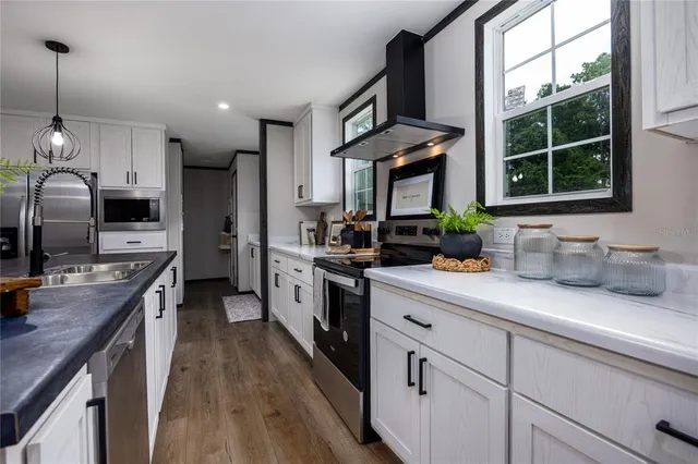 a kitchen with kitchen island granite countertop a sink a counter space appliances and cabinets
