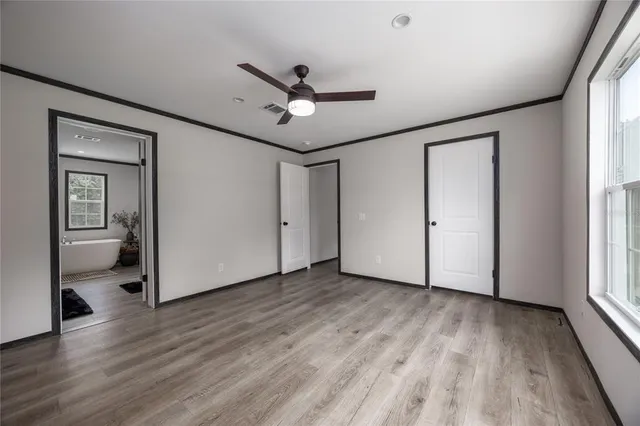 a view of empty room with wooden floor and fan