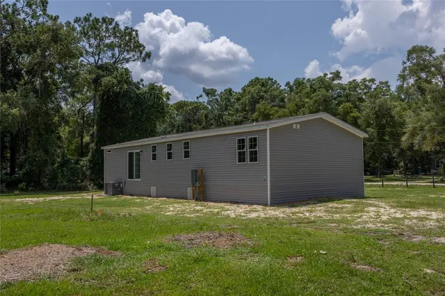 a house that is sitting in the grass with large trees