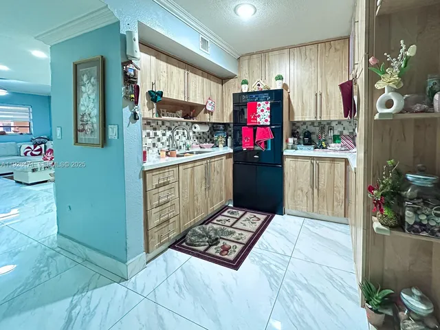 a living room with stainless steel appliances furniture and a kitchen view