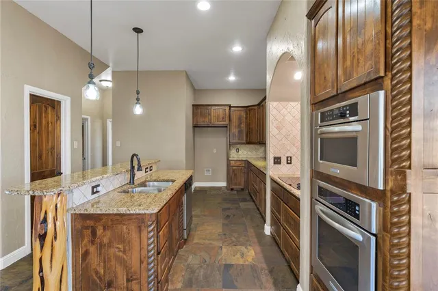 a kitchen with kitchen island granite countertop a sink stainless steel appliances and chandelier