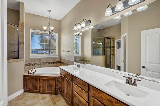 a spacious bathroom with a sink double vanity granite tub shower and a mirror