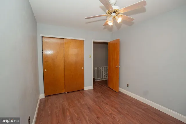 an empty room with wooden floor and a ceiling fan