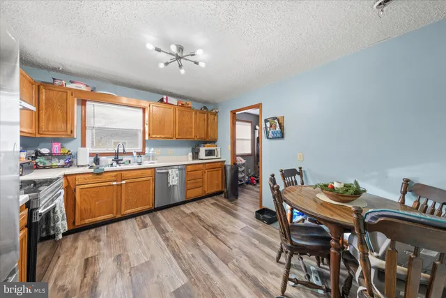 a kitchen with stainless steel appliances granite countertop a stove top oven a sink with dining table and chairs