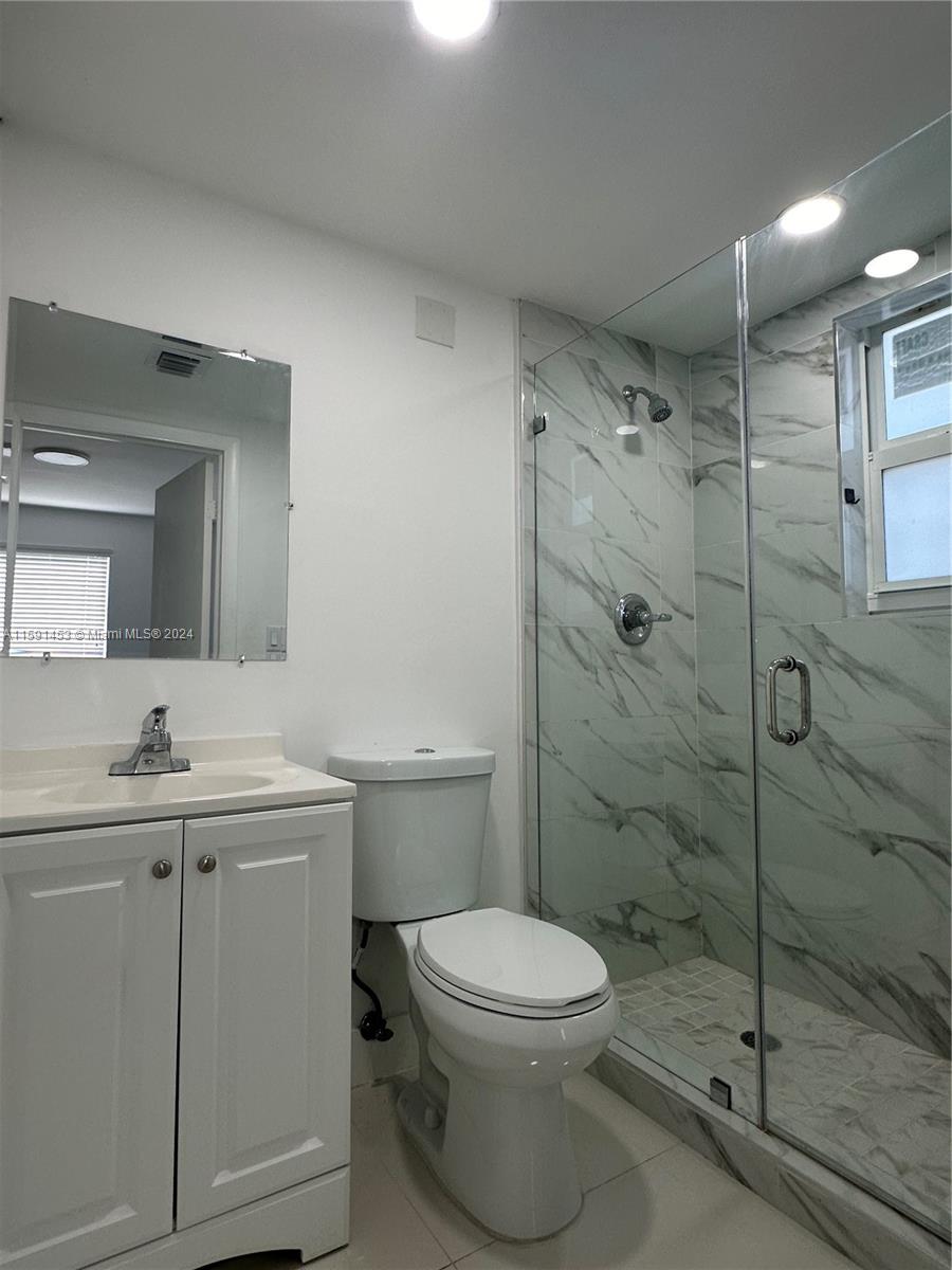502 Southwest 27th Avenue, Unit 4 Miami, FL 33135 - Photo 8 of 11 a bathroom with a granite countertop toilet a sink a mirror and shower