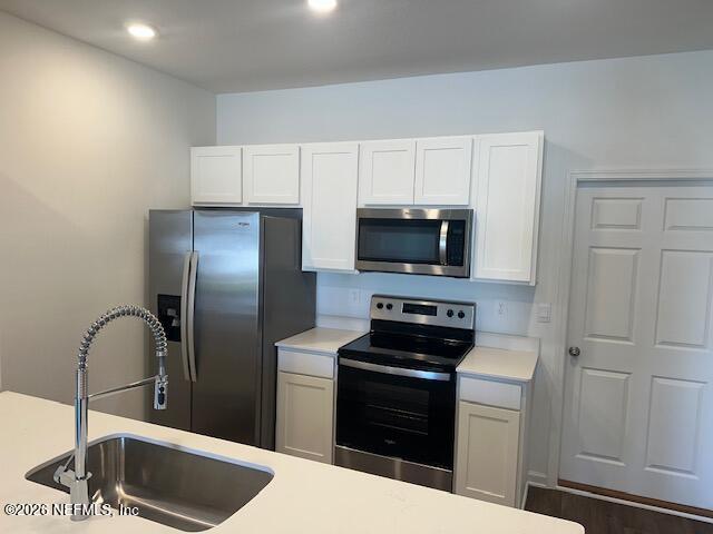 915 Rivertree Place Middleburg, FL 32068 - Photo 14 of 23 a kitchen with stainless steel appliances kitchen island granite countertop a refrigerator a sink a stove and white cabinets