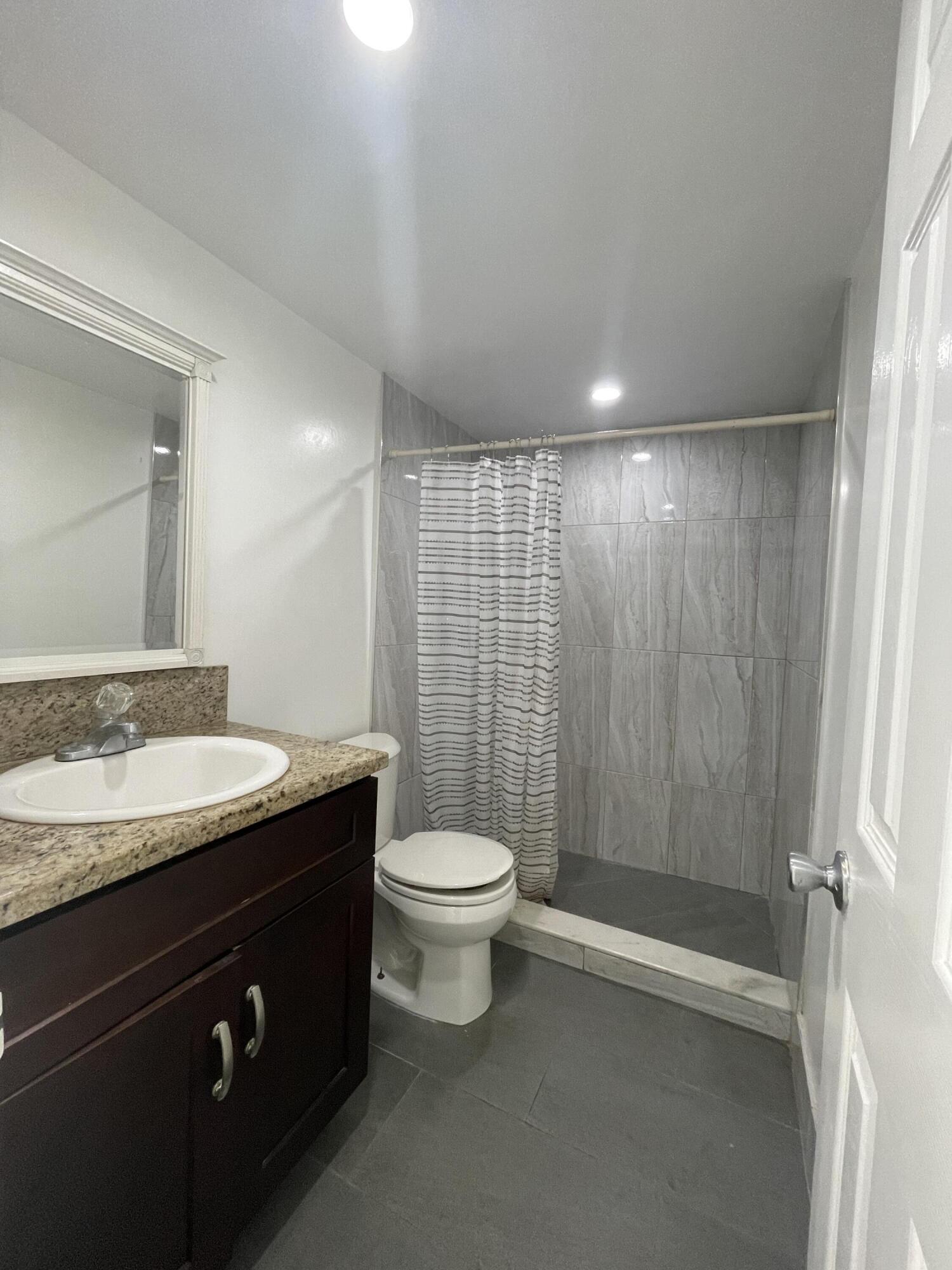 636 Northwest 13th Street, Unit 380 Boca Raton, FL 33486 - Photo 12 of 14 a bathroom with a granite countertop sink toilet and shower
