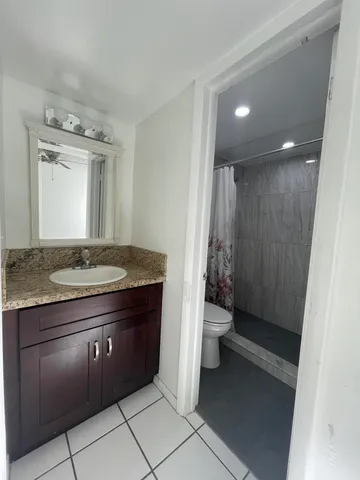a bathroom with a granite countertop sink a toilet a mirror and a vanity