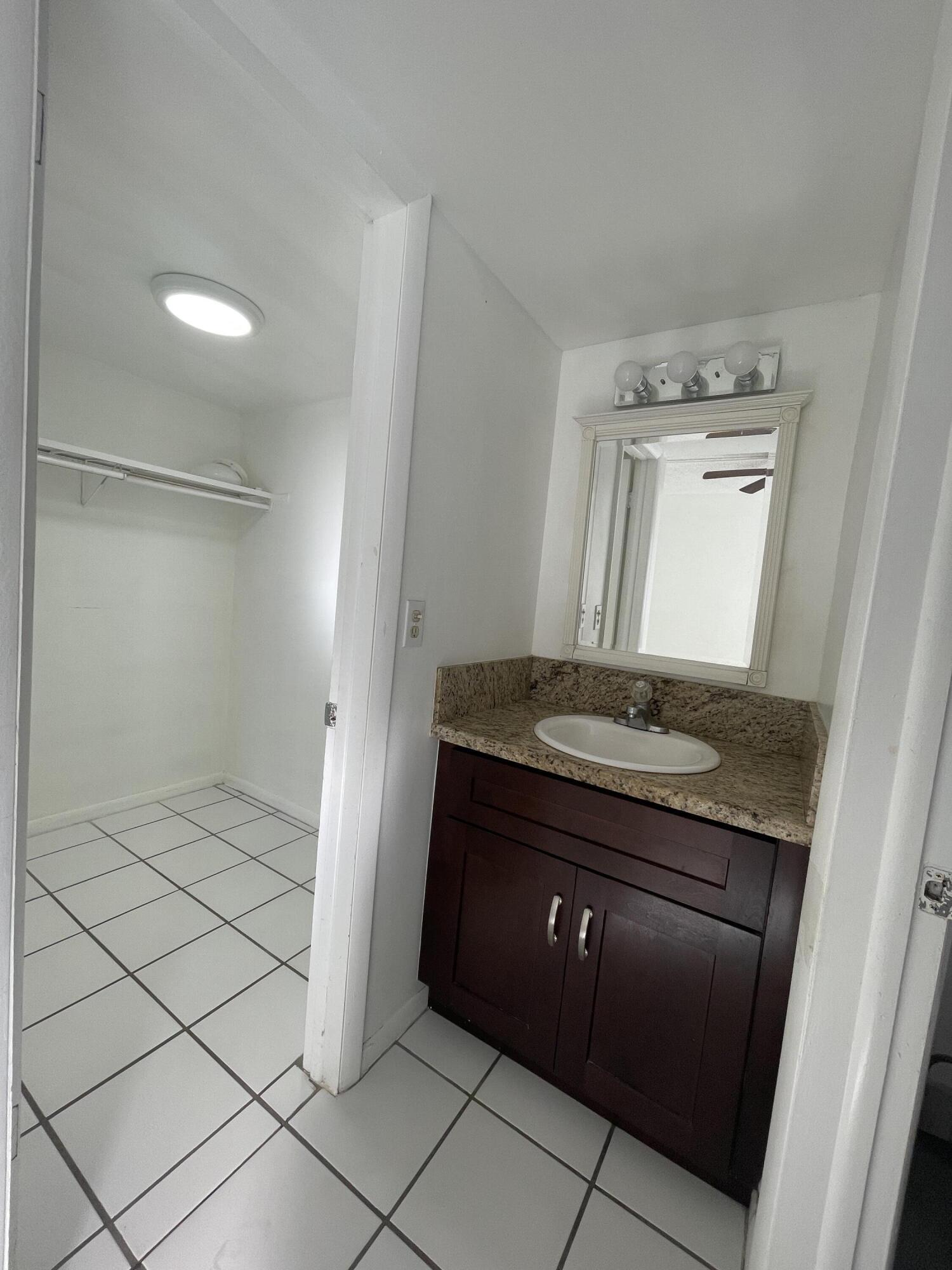 636 Northwest 13th Street, Unit 380 Boca Raton, FL 33486 - Photo 9 of 14 a bathroom with a granite countertop sink and a mirror