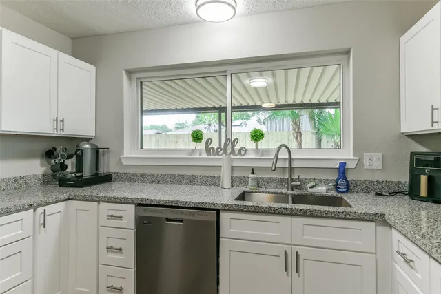 a kitchen with granite countertop a sink window and cabinets