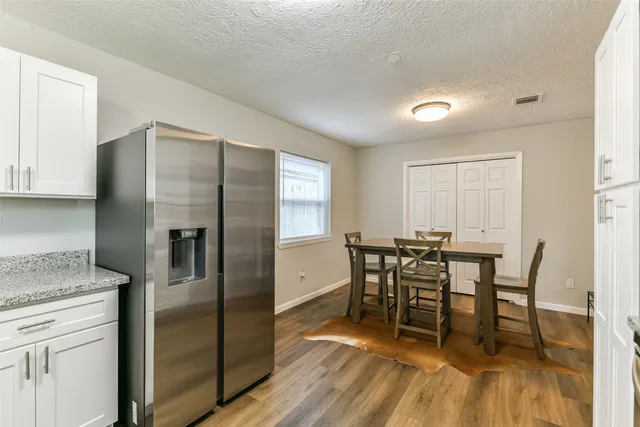 a kitchen with stainless steel appliances granite countertop a dining table chairs refrigerator and sink