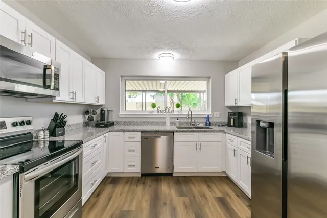 a kitchen with white cabinets appliances and a sink