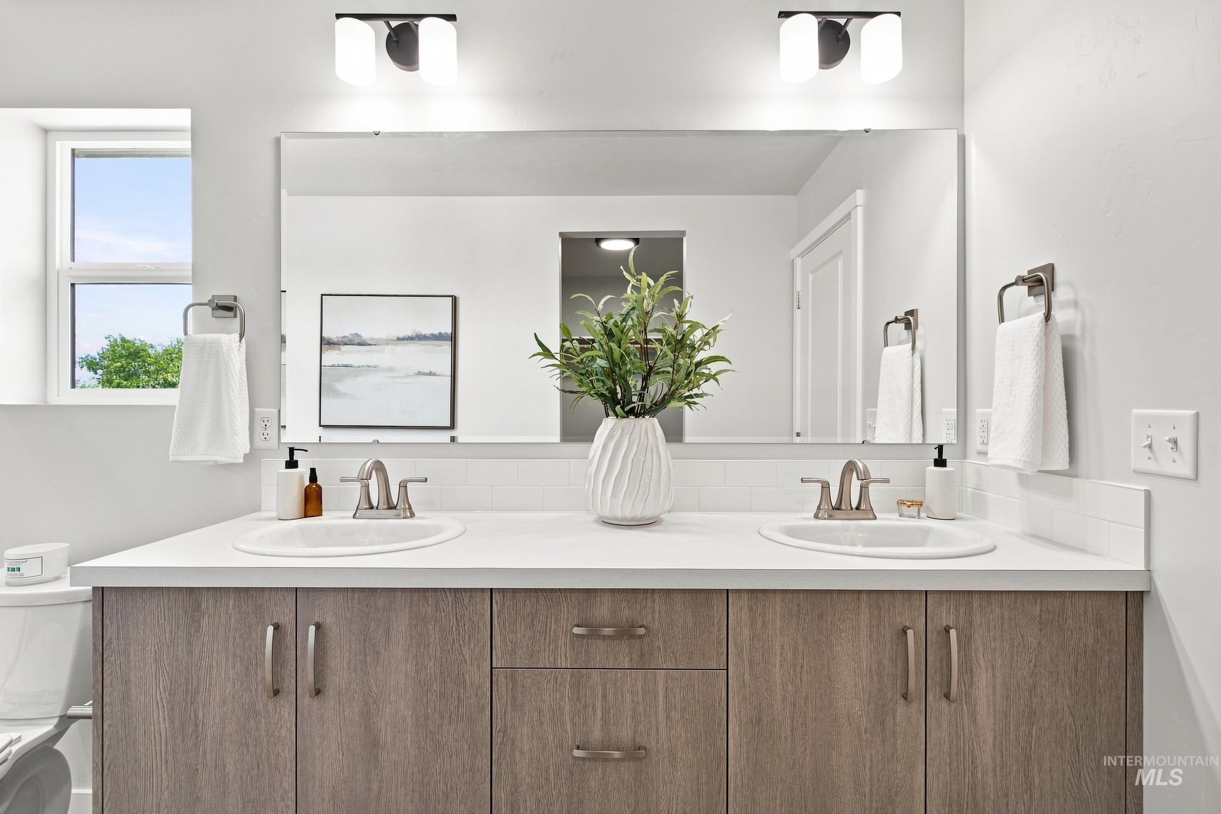 14044 Shiny Spruce Street Caldwell, ID 83607 - Photo 34 of 37 Dual vanity with undermount sinks, contemporary wood-finish cabinetry, and a full-width mirror
