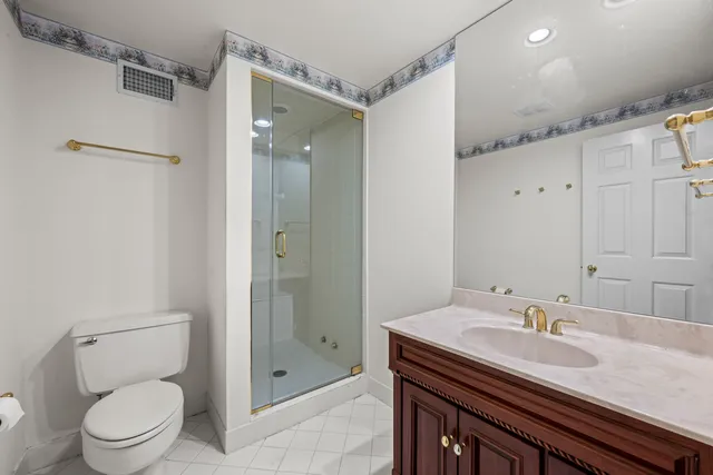 a bathroom with a granite countertop sink a toilet a mirror and shower