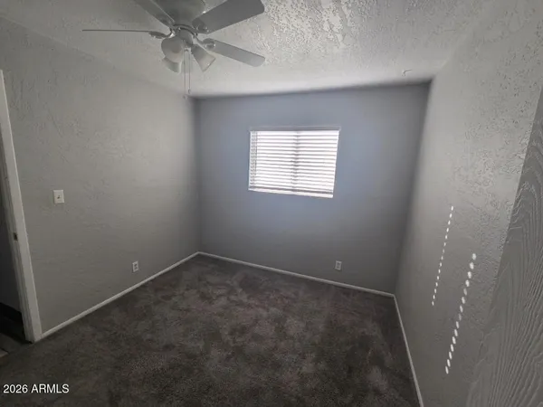 an empty room with a ceiling fan and carpet