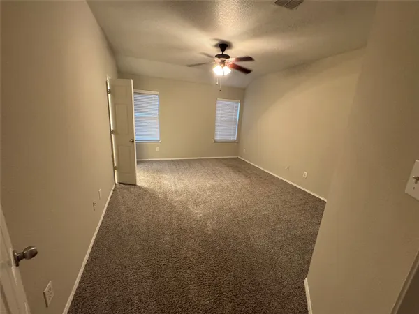 a view of an empty room with a chandelier fan