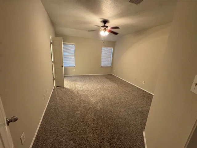 a view of an empty room with a chandelier fan