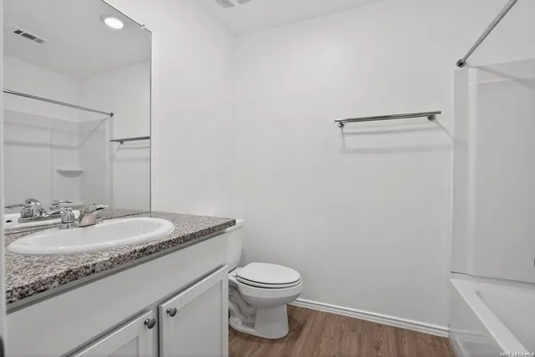 a bathroom with a granite countertop toilet a sink and a mirror