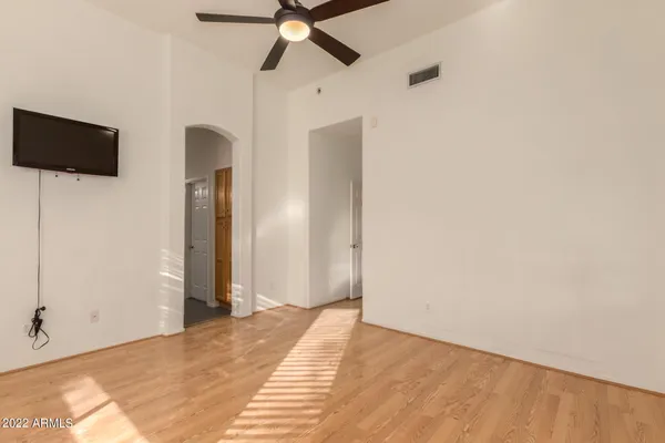 a view of empty room with wooden floor and fan
