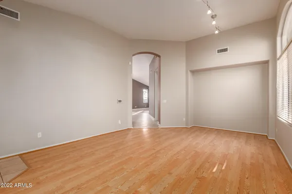 a view of empty room with wooden floor and fan