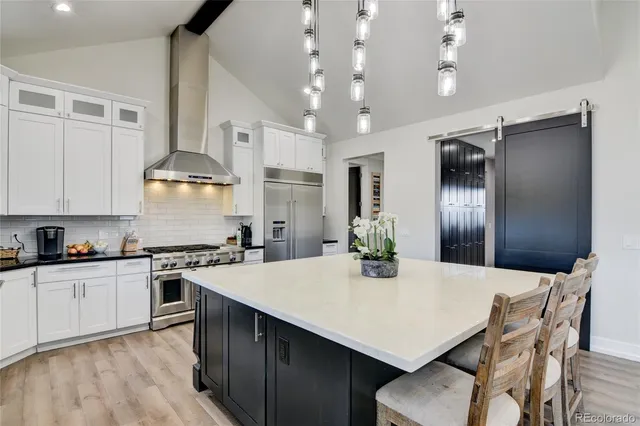 a kitchen with granite countertop a center island a stove a refrigerator cabinets a dining table and chairs