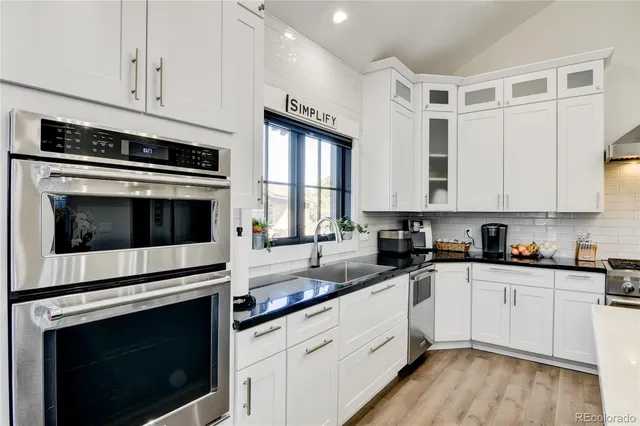 a kitchen with granite countertop white cabinets stainless steel appliances and sink