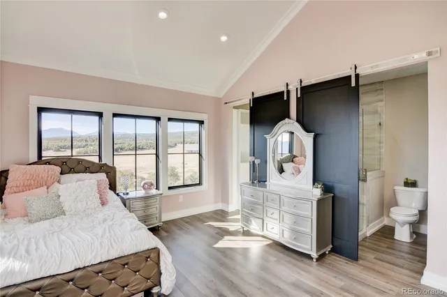 a spacious bedroom with a bed a mirror and a large window