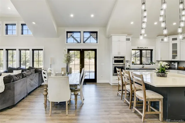 a dining room with furniture wooden floor and a kitchen view