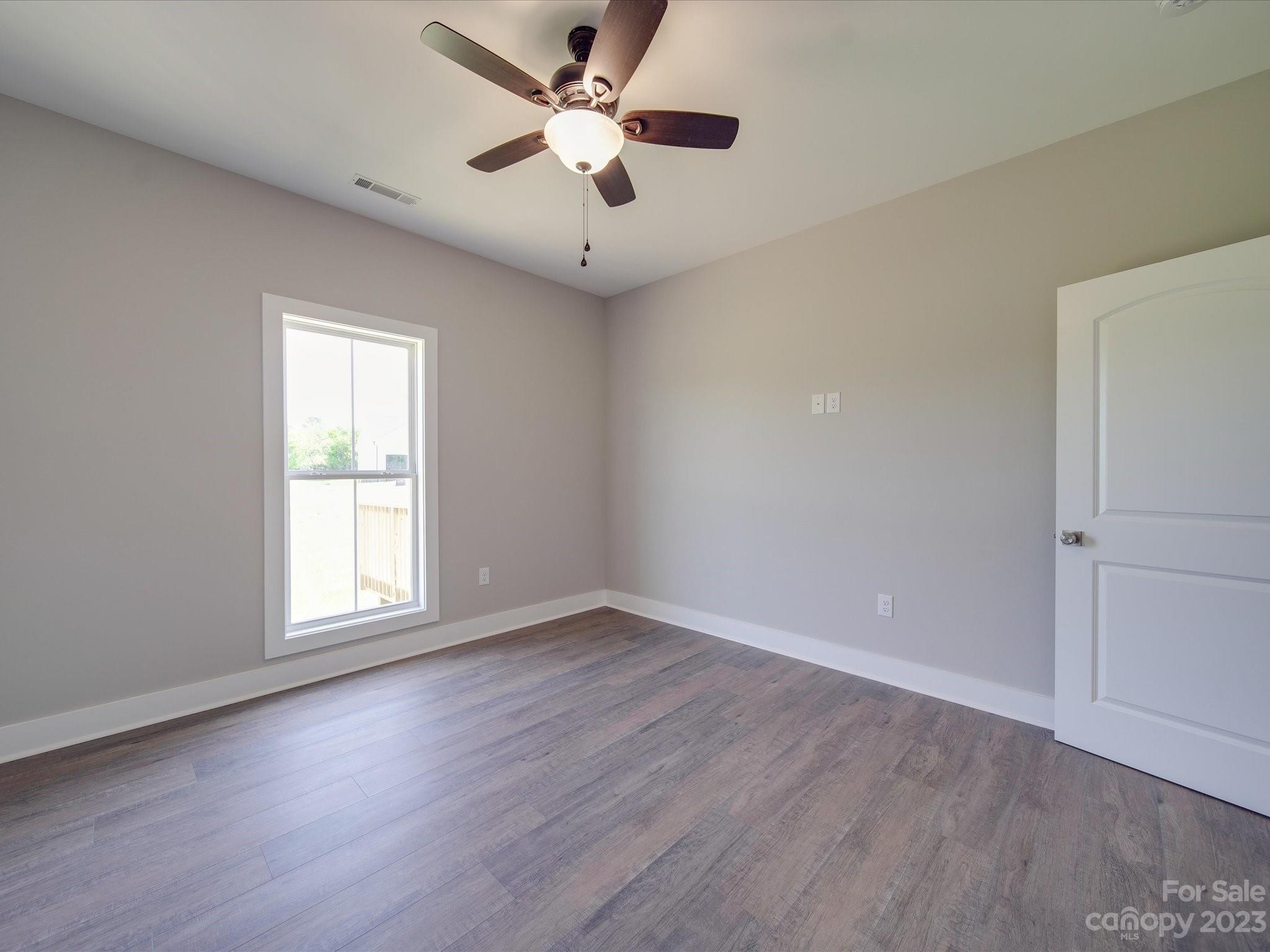 1321 Stack Road Monroe, NC 28112 - Photo 23 of 33 an empty room with wooden floor ceiling fan and windows