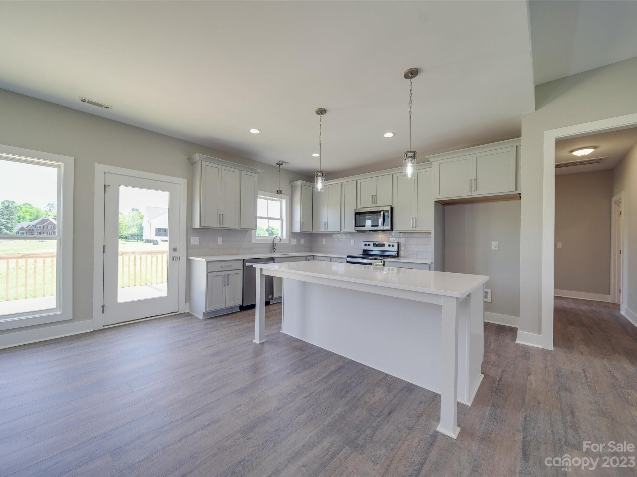 1321 Stack Road Monroe, NC 28112 - Photo 7 of 33 a view of kitchen with granite countertop refrigerator oven sink and white cabinets with wooden floor