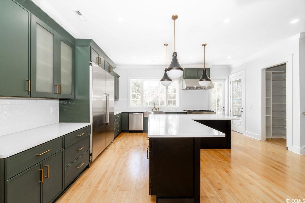 511 Rice Bluff Road Pawleys Island, SC 29585 - Photo 4 of 40 Kitchen featuring ornamental molding, quartz countertops, island, and stainless steel appliances