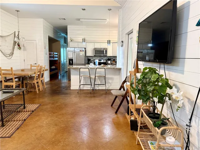 a living room with furniture a flat screen tv and kitchen view