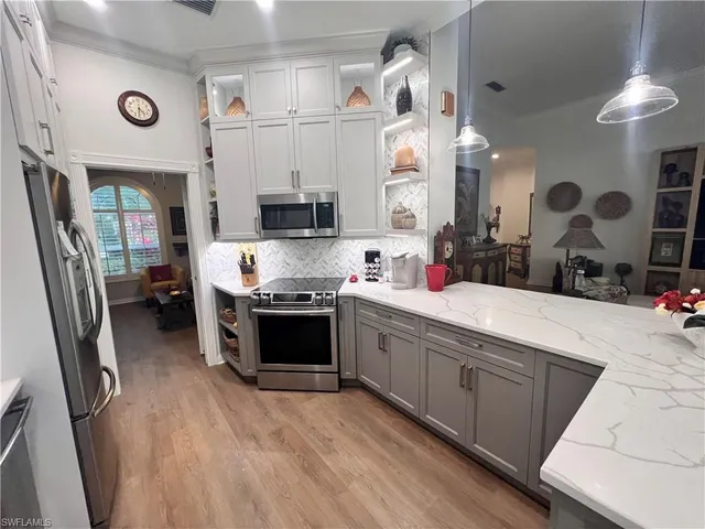 a large kitchen with stainless steel appliances a stove a sink dishwasher and a fireplace with wooden floor