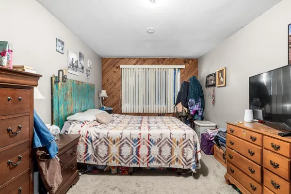a bedroom with a bed and a flat tv screen on the dresser