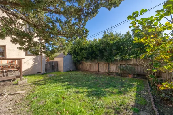 a view of a backyard with a house and large trees with wooden fence