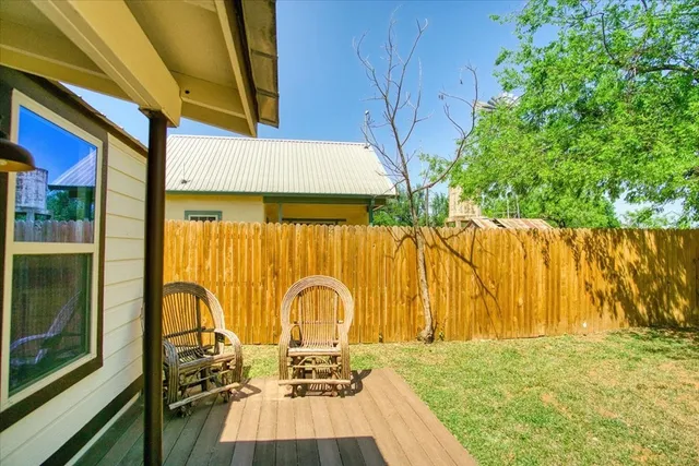 a view of a patio with table and chairs with wooden floor and fence