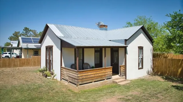 a view of house with backyard and trees in the background
