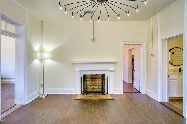 a view of an empty room with wooden floor fireplace and a window