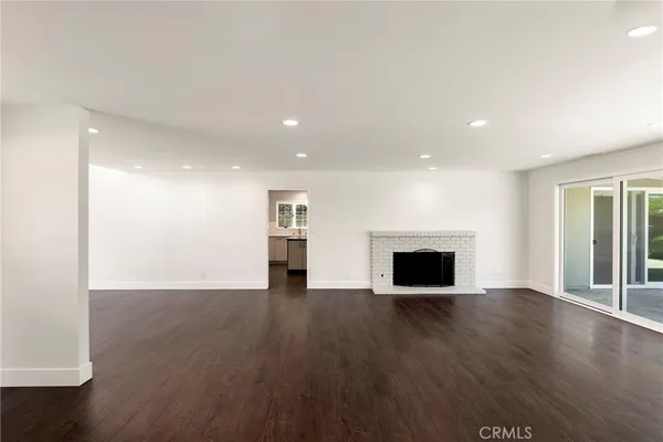 an empty room with wooden floor fireplace and windows