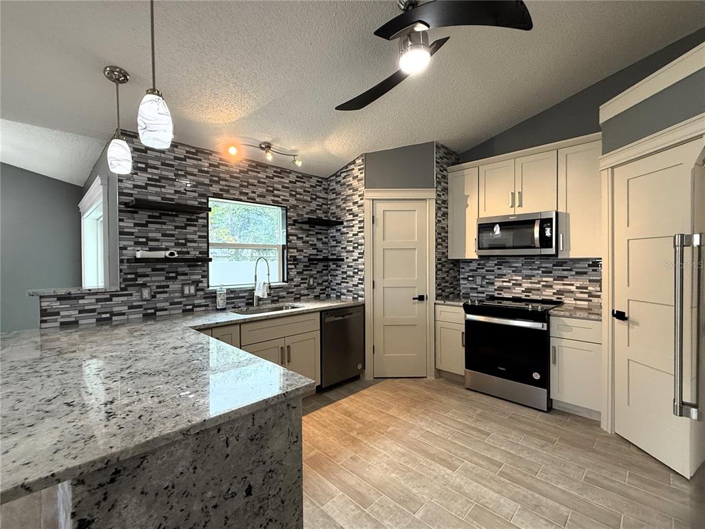 6172 Raleigh Street Spring Hill, FL 34606 - Photo 21 of 64 a kitchen with stainless steel appliances granite countertop a stove a sink and a refrigerator