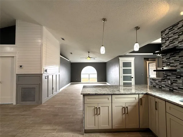 an empty room with wooden floor chandelier and windows