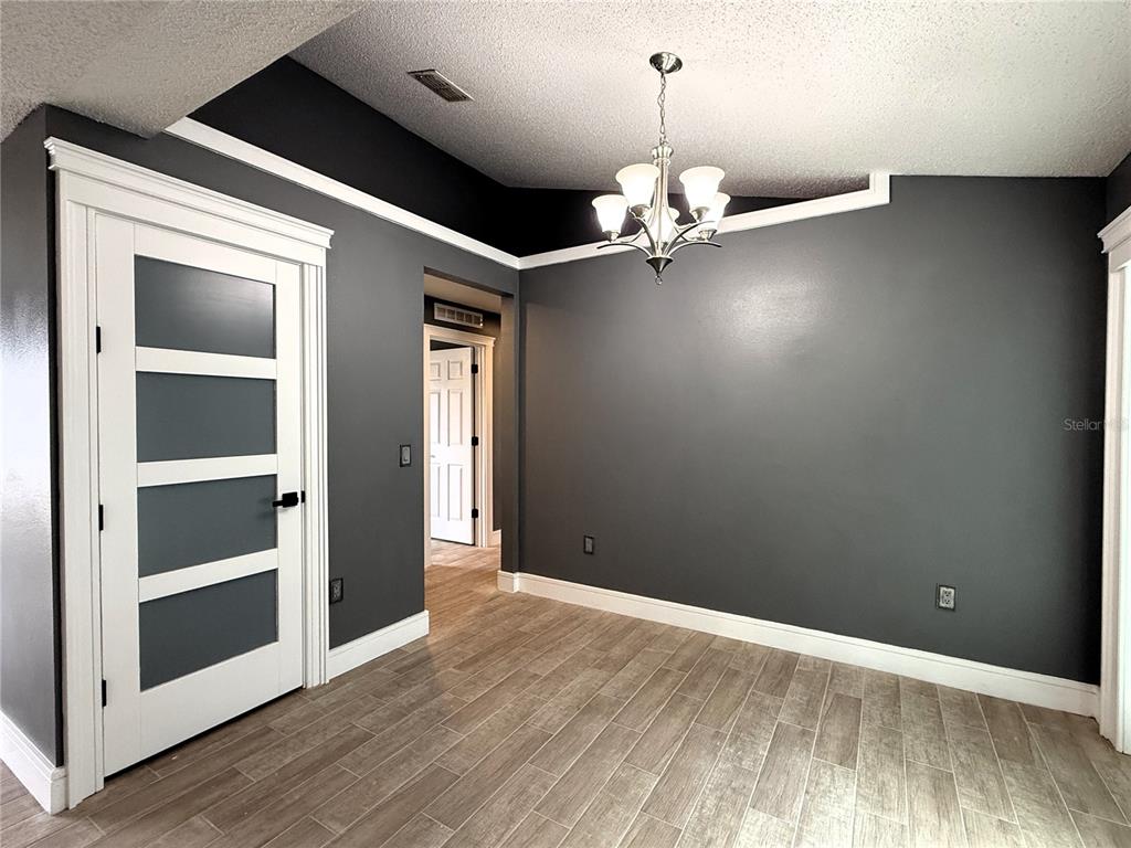 6172 Raleigh Street Spring Hill, FL 34606 - Photo 28 of 64 an empty room with wooden floor chandelier and windows