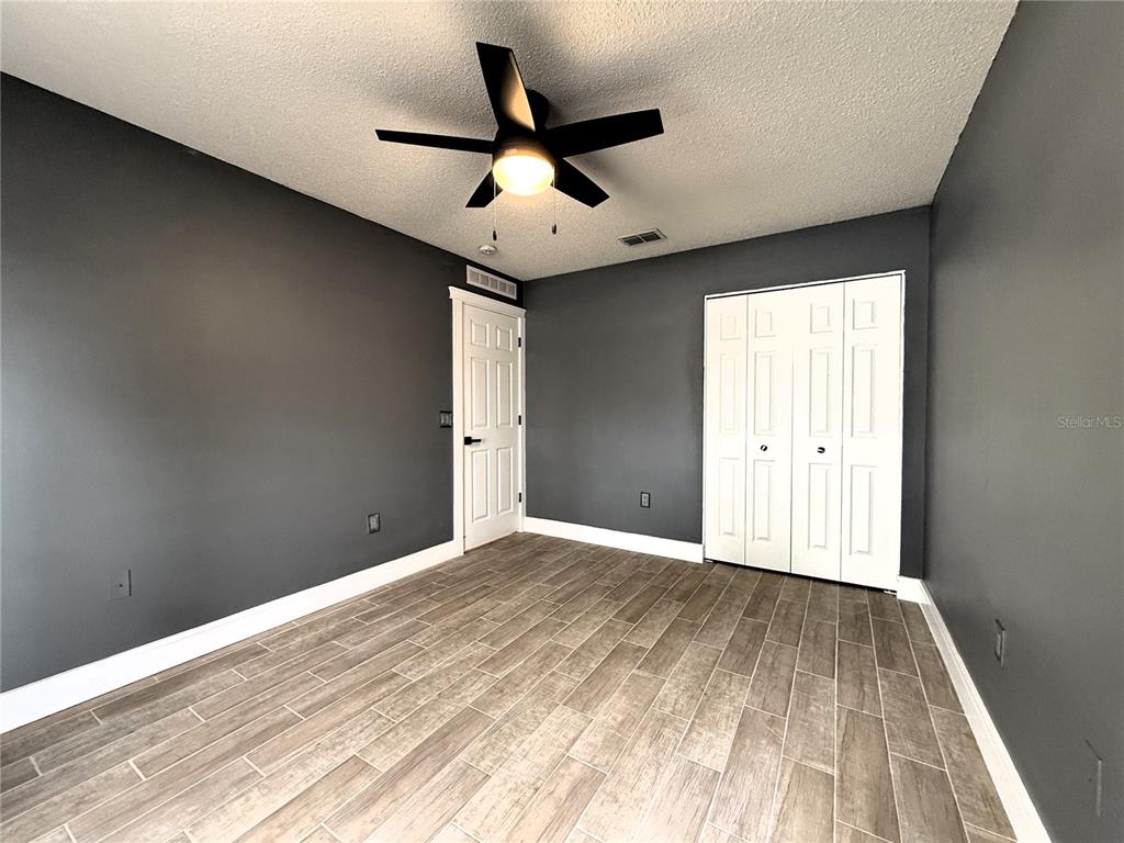 6172 Raleigh Street Spring Hill, FL 34606 - Photo 32 of 64 an empty room with wooden floor ceiling fan and windows